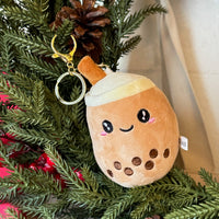 Plush toy resembling a bubble tea with a keychain on a Christmas tree.