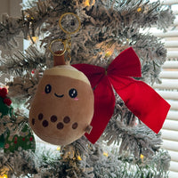 Plush toy with a red bow attached to a Christmas tree