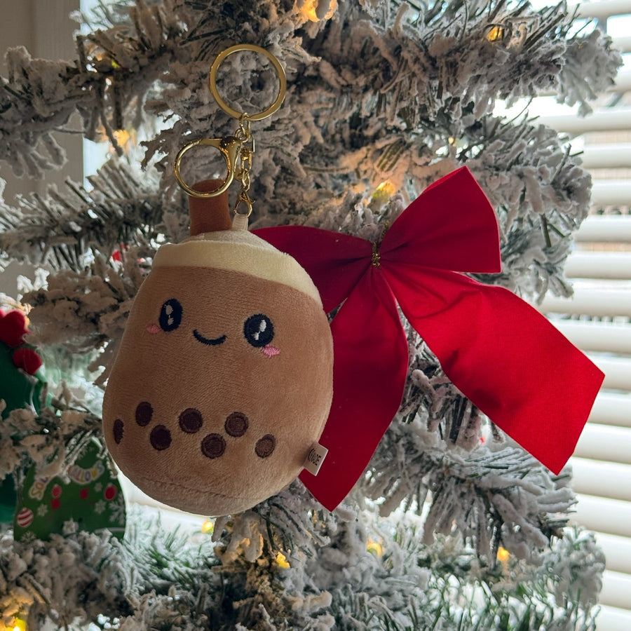 Plush toy with a red bow attached to a Christmas tree