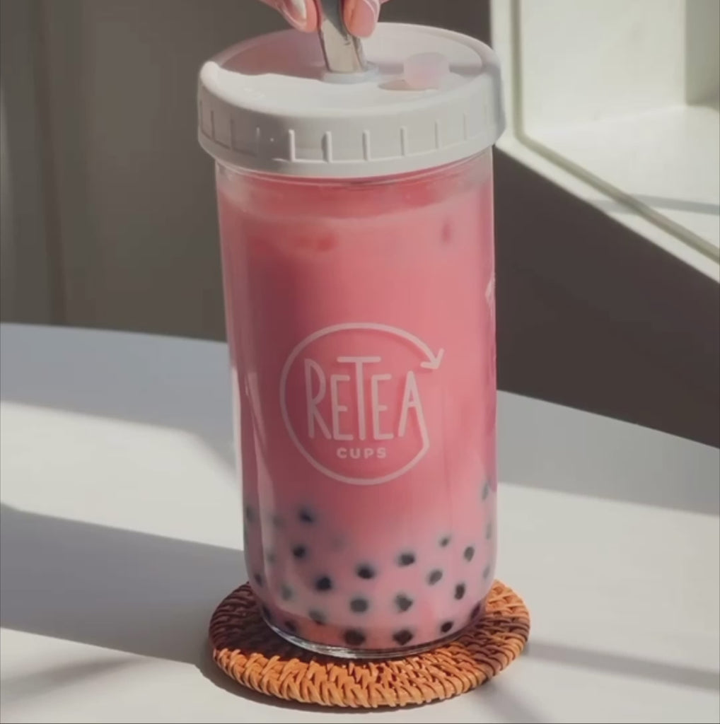 Video: Strawberry milk tea package unboxing reveals recyclable paper packaged creamer powder, dark brown sugar, strawberry milk tea powder, uncooked tapioca. Add 3 tablespoons of strawberry milk tea powder poured into clear glass reusable Retea cup, added one tablespoon of lactose-free creamer, added 250 milliliters of hot water, stir until well mixed, add 250 milliliters of ice, put on non-leak plastic lid and shake until milk tea cools, add cooked tapioca, stir with silver metal bubble tea straw