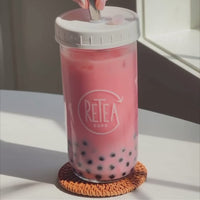 Video: Strawberry milk tea package unboxing reveals recyclable paper packaged creamer powder, dark brown sugar, strawberry milk tea powder, uncooked tapioca. Add 3 tablespoons of strawberry milk tea powder poured into clear glass reusable Retea cup, added one tablespoon of lactose-free creamer, added 250 milliliters of hot water, stir until well mixed, add 250 milliliters of ice, put on non-leak plastic lid and shake until milk tea cools, add cooked tapioca, stir with silver metal bubble tea straw