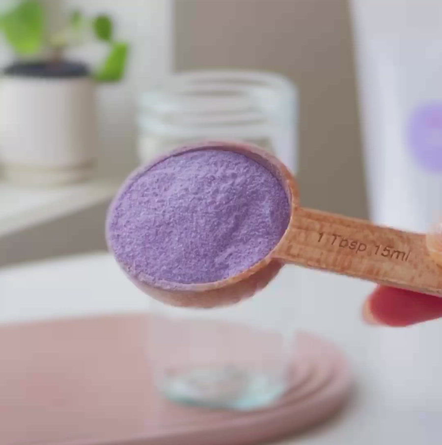 Tutorial on how to make taro bubble tea, 3 tablespoons of taro milk tea powder poured into clear glass reusable Retea cup, added one tablespoon of lactose-free creamer, added 250ml of hot water, stir until well mixed, add 250ml of ice, put on non-leak plastic lid and shake until milk tea cools, add cooked tapioca, stir with rainbow stainless steel boba straw